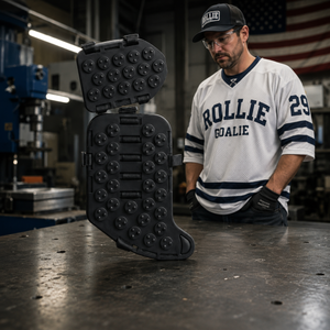 Person wearing a 'Rollie Goalie' jersey with a large black boot on a table in an industrial setting.