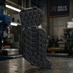A black molded plastic training or utility case standing upright on a workshop table, with its hinged lid propped open above it. The case has multiple circular recessed details and a rugged industrial design.